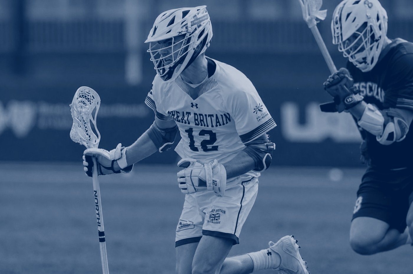 Great Britain lacrosse player carrying the ball under pressure
